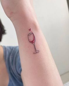 a woman's arm with a small wine glass tattoo on it