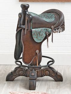 a brown and blue saddle sitting on top of a wooden stand