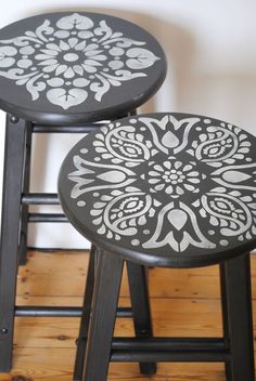 two black and white stools sitting next to each other on top of a wooden floor