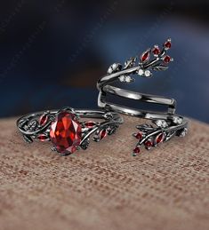 two silver rings with red stones and leaves on the top one has a stone in the middle