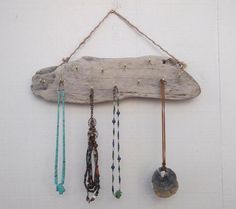 several necklaces are hanging on a piece of driftwood that is attached to a wall