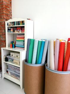 two bins with different types of fabric in them next to a book shelf filled with books