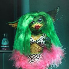 a doll with green hair and pink feathers