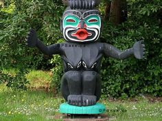 a statue in the shape of a totem stands in front of some bushes and trees