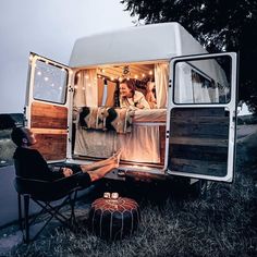 a person sitting in a chair next to a camper