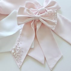 two pink and white bows with pearls are on the table, next to each other