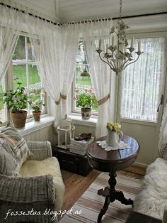 a living room filled with furniture and windows covered in white sheer curtained drapes