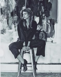 a black and white photo of a woman sitting on a stool