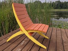 an orange and yellow lawn chair sitting on top of a wooden deck next to water