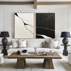 a living room filled with white furniture and paintings on the wall above it's coffee table