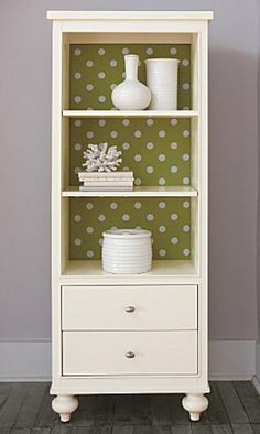 a white bookcase with polka dot wallpaper