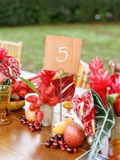 a wooden table topped with fruit and flowers next to a number 5 on a sign