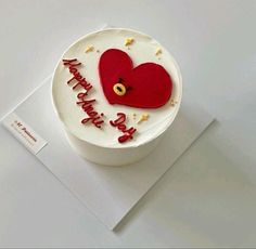 a white cake with a red heart on it