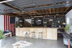 the inside of a garage with an american flag on the wall and several stools