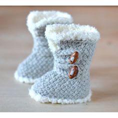 a pair of crocheted slippers with buttons on the inside and outside, sitting on a wooden surface