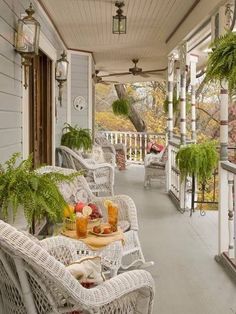 a porch with wicker furniture and potted plants on the front porch, along with hanging lanterns