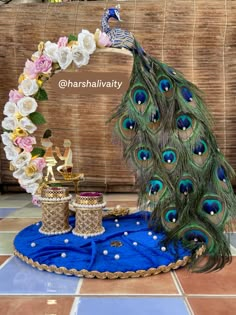 a peacock sitting on top of a blue blanket next to a vase filled with flowers