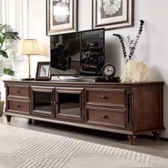 a living room scene with focus on the entertainment center and wall hangings above it