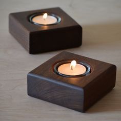 two wooden candles are sitting on a table with one candle in the center and another burning