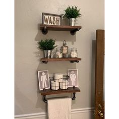 two wooden shelves with towels, potted plants and pictures on them in a bathroom