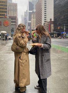 two women standing in the rain talking to each other