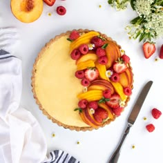 there is a pie with fruit on top and flowers around the edges next to it