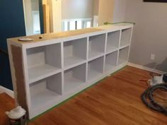 an empty room with white shelving in the middle and hard wood flooring on the other side