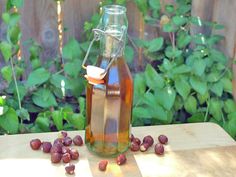 a glass bottle filled with liquid sitting on top of a wooden table next to grapes