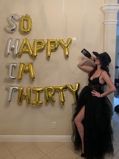 a woman in a black dress is standing next to balloons that say happy birthday and the words so happy it's thirty