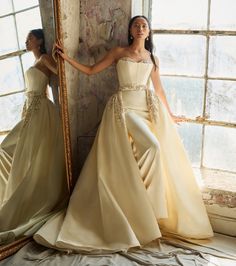 a woman in a dress standing next to a mirror