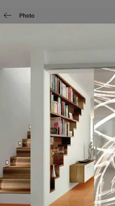 an open door leading to a room with stairs and bookshelves