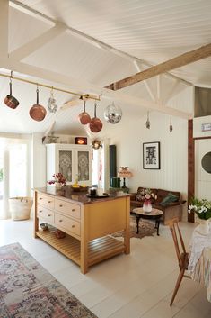 an open kitchen and living room area with white walls, wood ceilinging and exposed beams