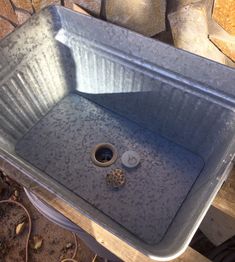 a metal sink sitting on top of a wooden table next to some rocks and stones