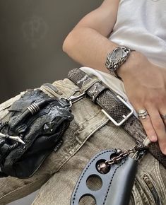 a person with their hand on the back of his pants holding a purse and chain