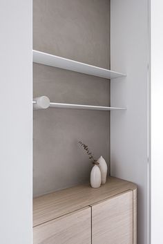 a white vase sitting on top of a wooden dresser next to a wall mounted shelf