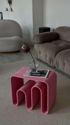 a pink coffee table sitting on top of a carpeted floor next to a couch