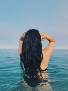 the back of a woman's head is shown in the middle of the water