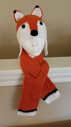 a knitted fox hat and scarf hanging on a wall