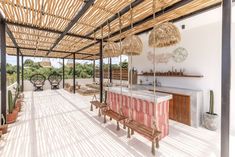 an outdoor kitchen with hanging plants and potted plants on the counter top, in front of a covered patio area