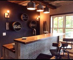 a bar with stools in front of it and several lights hanging from the ceiling