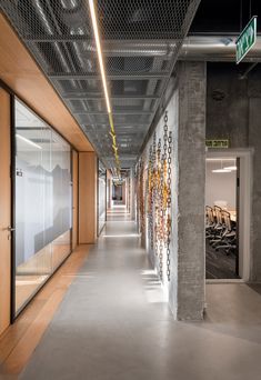 an empty hallway with glass doors and wood paneling on the walls, leading to two rows of desks