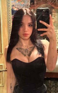 a woman taking a selfie in front of a mirror wearing a black corset