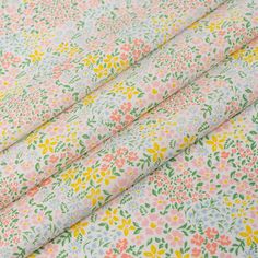 the fabric has flowers on it and is pink, yellow, green, blue and white