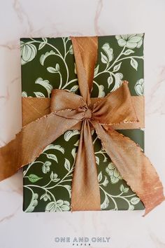 a present wrapped in green and brown paper with a bow on it's side