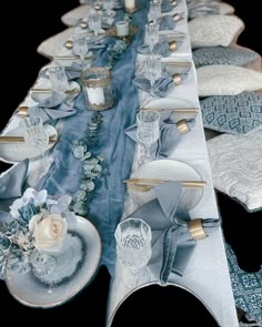 a long table is set with blue and white linens, silver plates and flowers