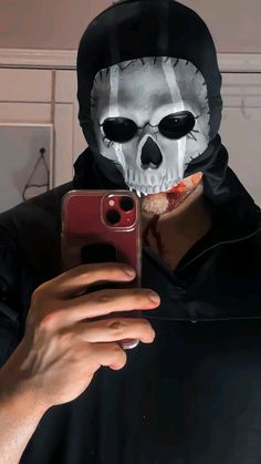 a person wearing a skeleton mask taking a selfie with a cell phone in their hand