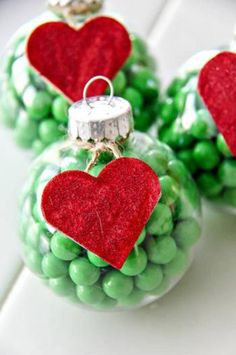 three glass ornaments with red hearts on them