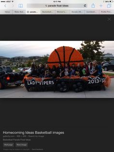 a group of people sitting on top of an orange basketball float in front of a building