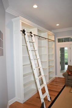 a ladder leaning up against a bookcase in a room with hardwood floors and white walls