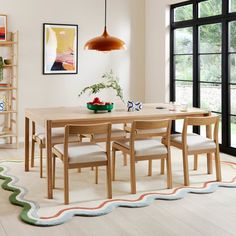 a dining room table and chairs in front of a large window with an open bookcase